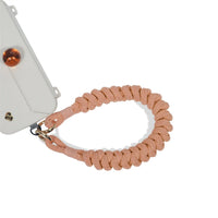 Safety wrist strap secured to phone port during movement in peach orange