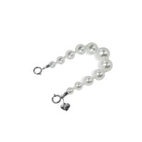Side view of small pearl charm strap, showcasing compact design for easy use.