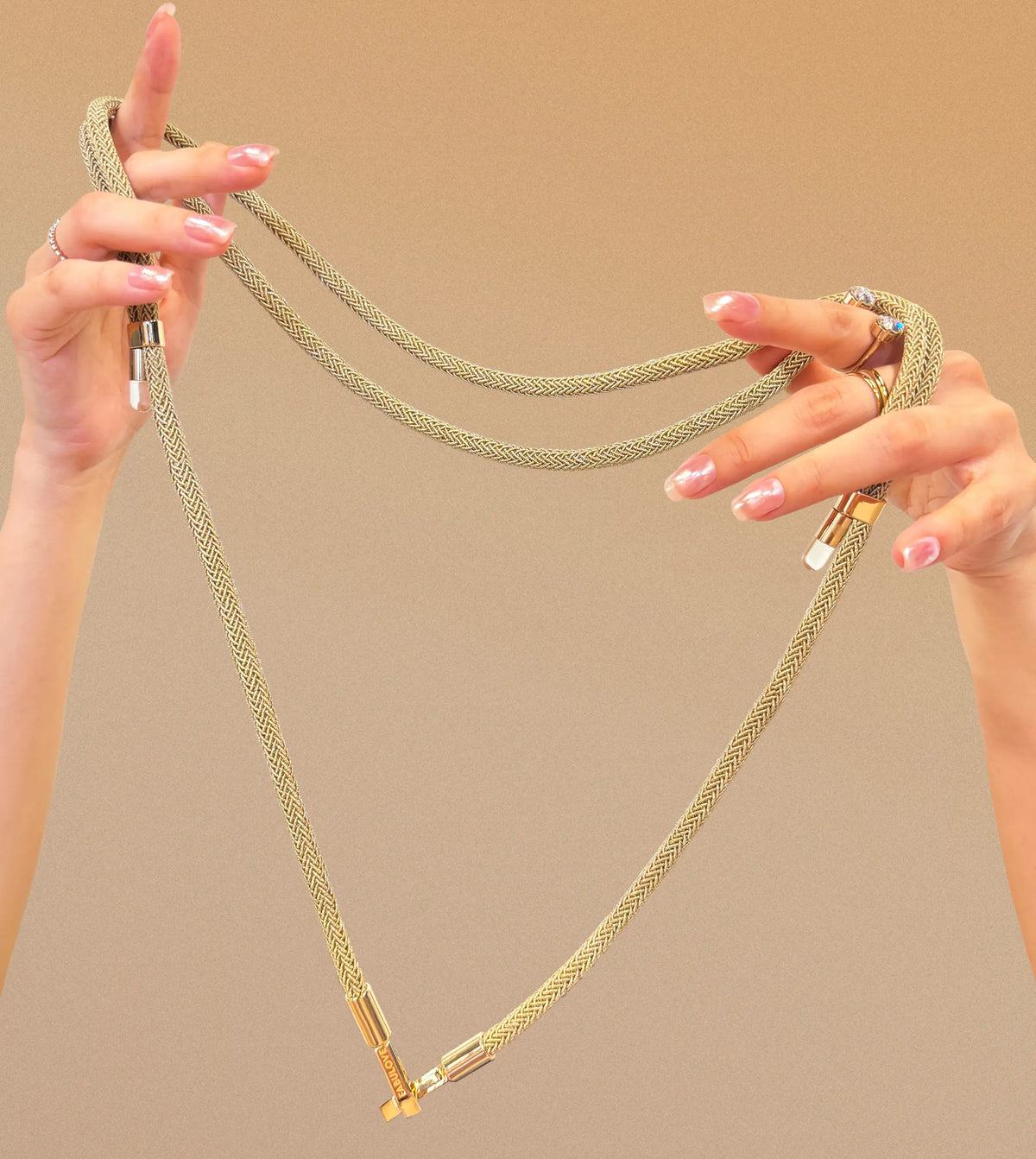 Fashionable hands with rings elevating golden Bling Bling crossbody strap, showcasing double-rope structure and tiny bulb design as buckles clasp together. BLING BLING STRAP.