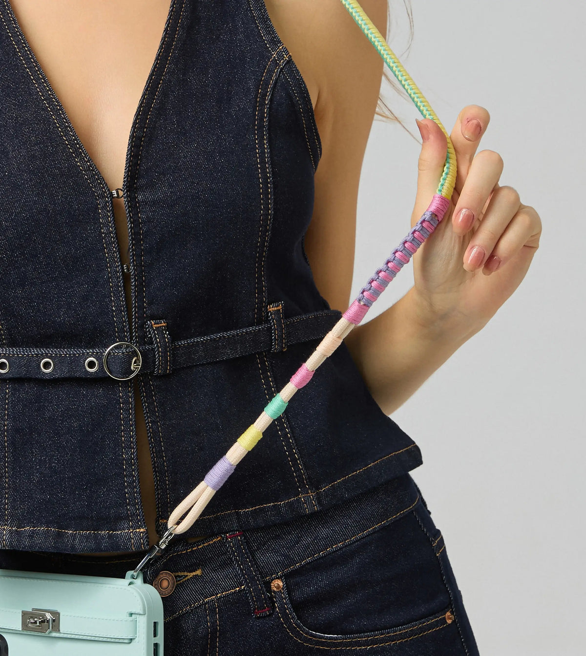 Close-up of Mint Mambo HAND-BRAIDED TENCEL™ crossbody strap on woman, fingers gently spreading ropes to reveal intricate texture. HAND-BRAIDED TENCEL™ CROSSBODY STRAP.
