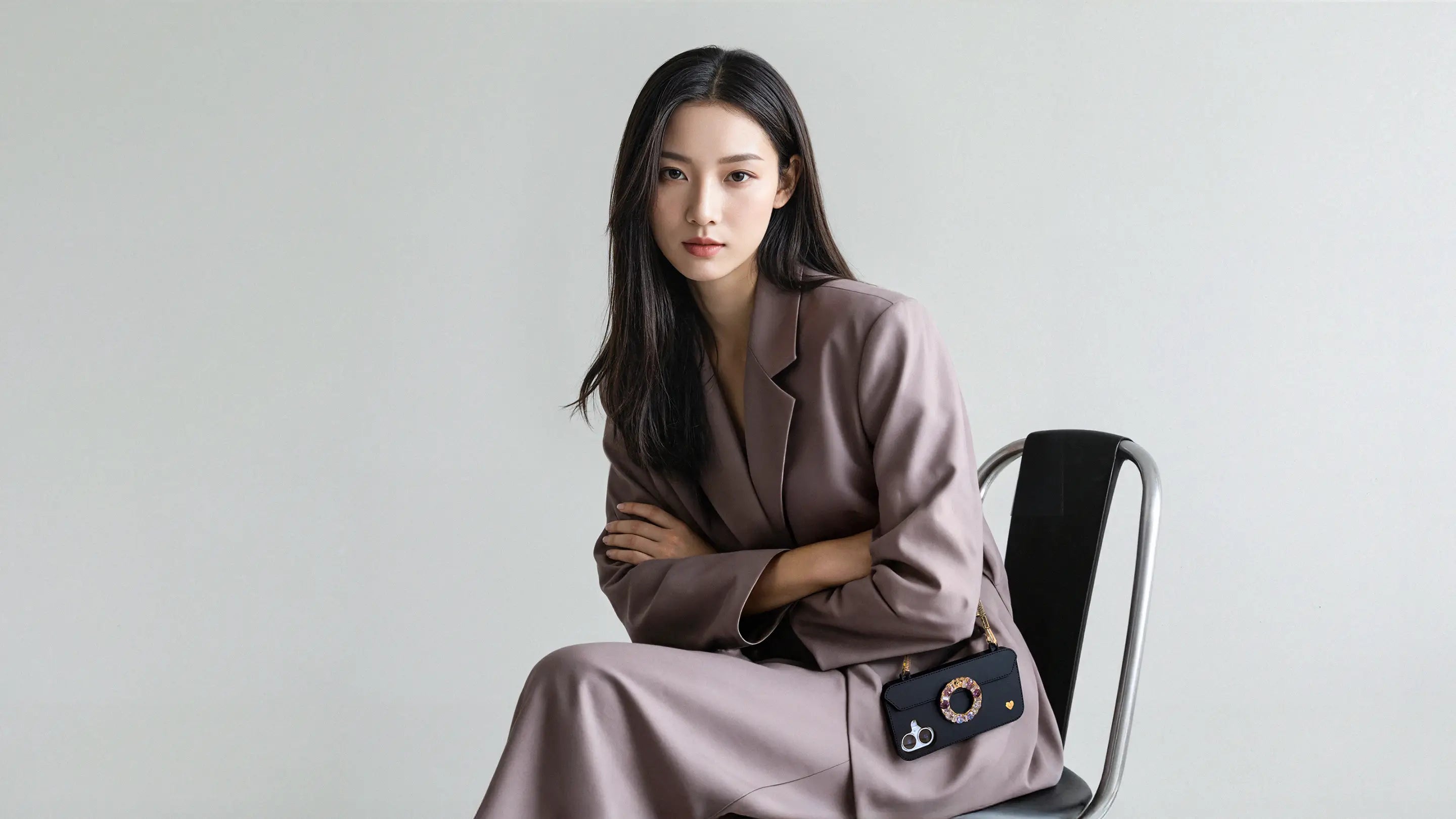 Professional woman seated in black chair holding golden Bling Bling Wristlet attached to Dreamscape Ring purse case via metal buckles. CONVENIENCE, REDEFINED.