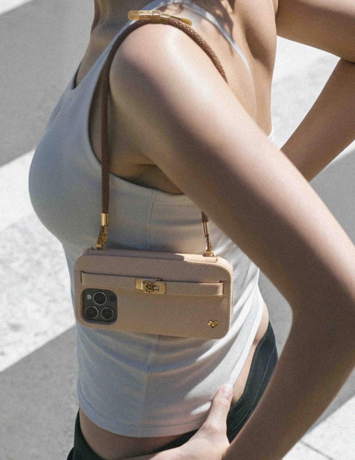 Beige LUMI purse case showcased on stylish woman walking, featuring strap-ready ears with caramel wristlet accent. IPHONE PURSE CASES.