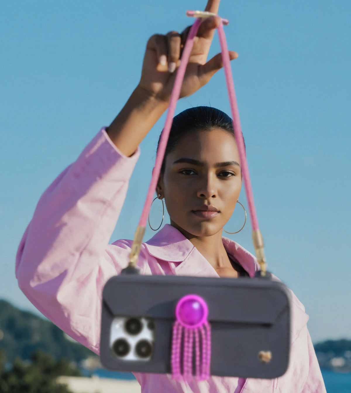 Fashion-forward woman at beach showcasing scarlet Bling Bling wristlet with Crystal Tassel Drop ornament on STYLEBASE case. MIX & MATCH YOUR PURSE CASE.